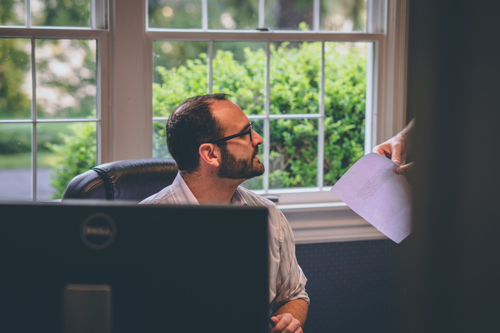 Man sitting discussing bias in performance reviews with standing colleague