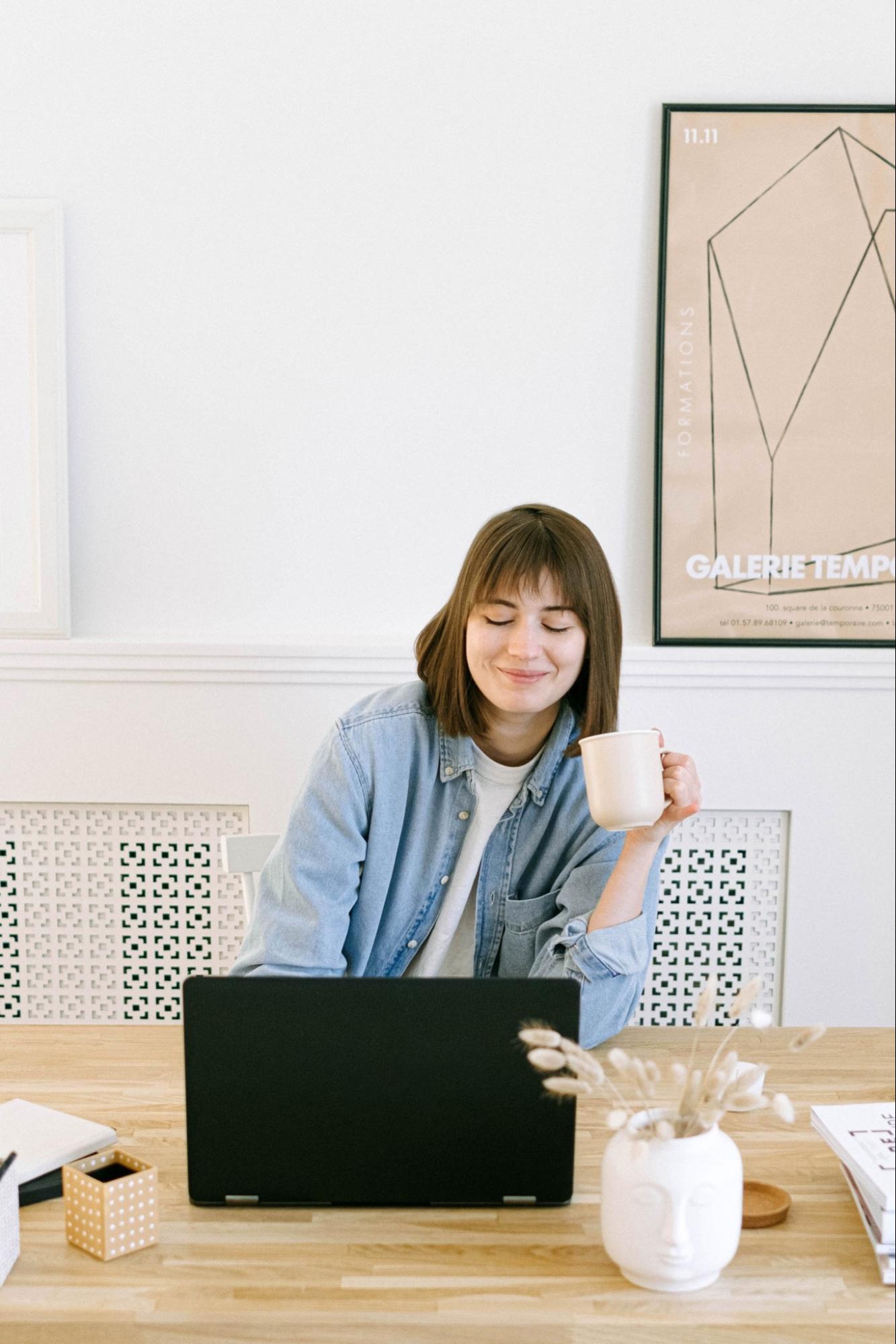 Woman with mug doing one-on-on meeting on laptop