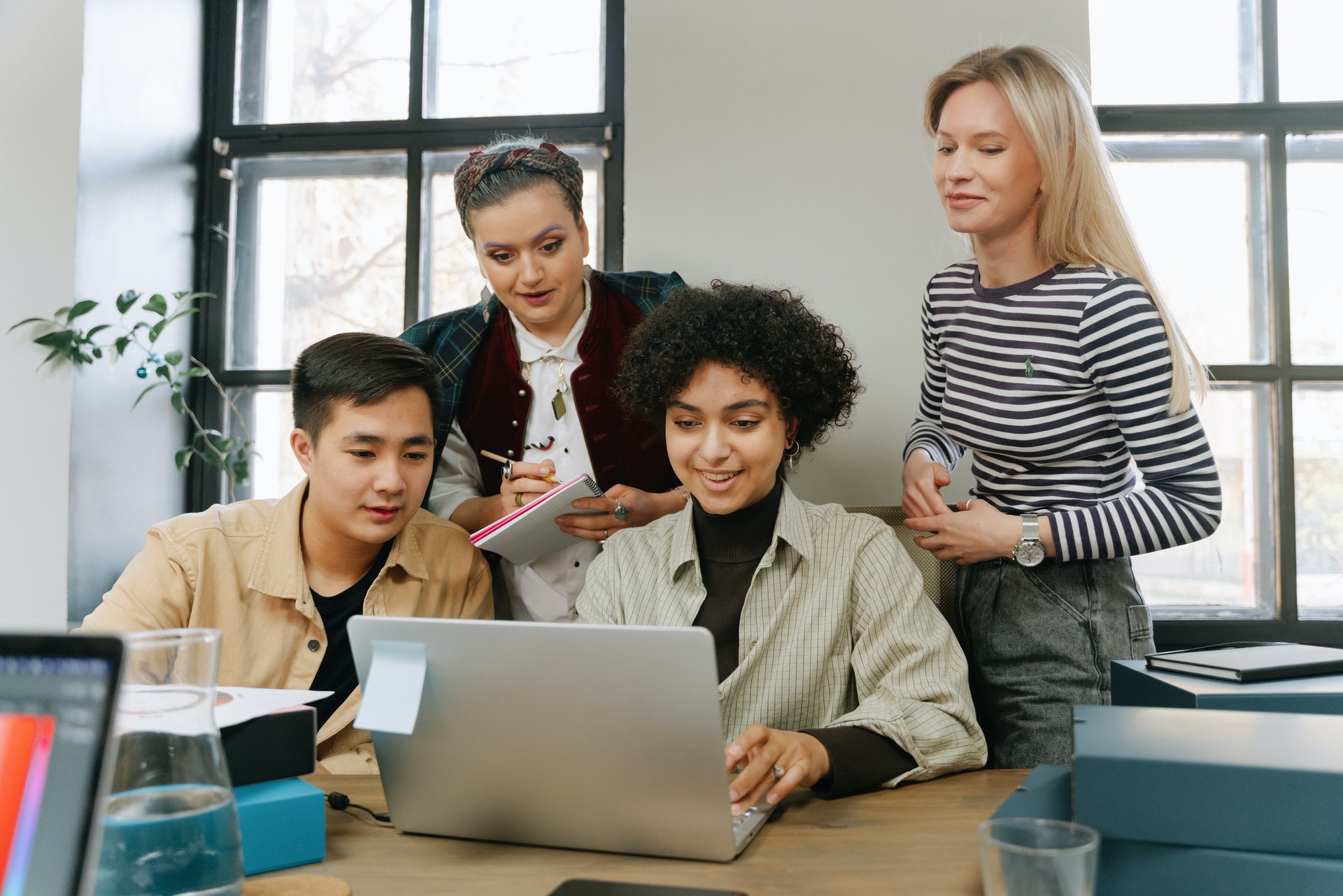 Four colleagues reviewing employee motivation survey on laptop