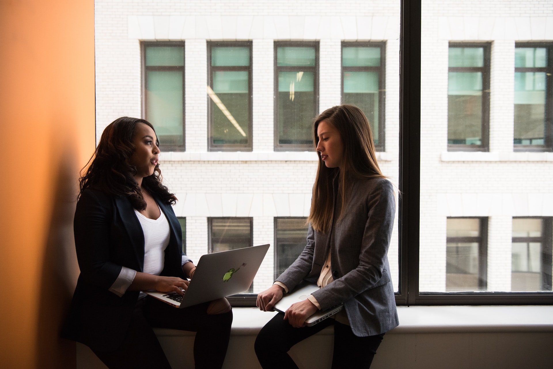 Black woman giving peer feedback to white woman colleague