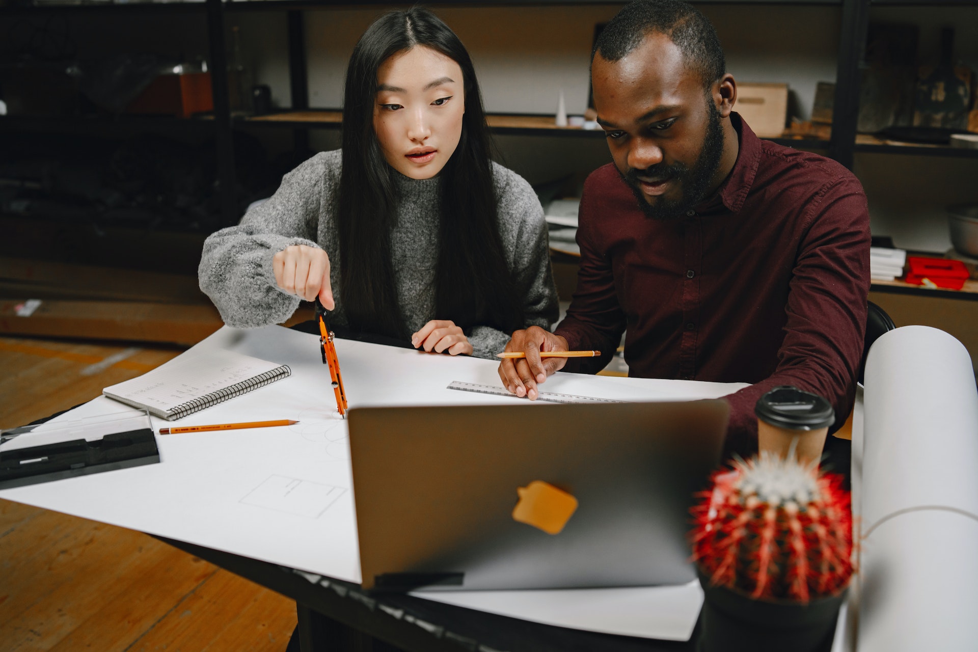 Black man Asian woman reviewing constructive feedback examples