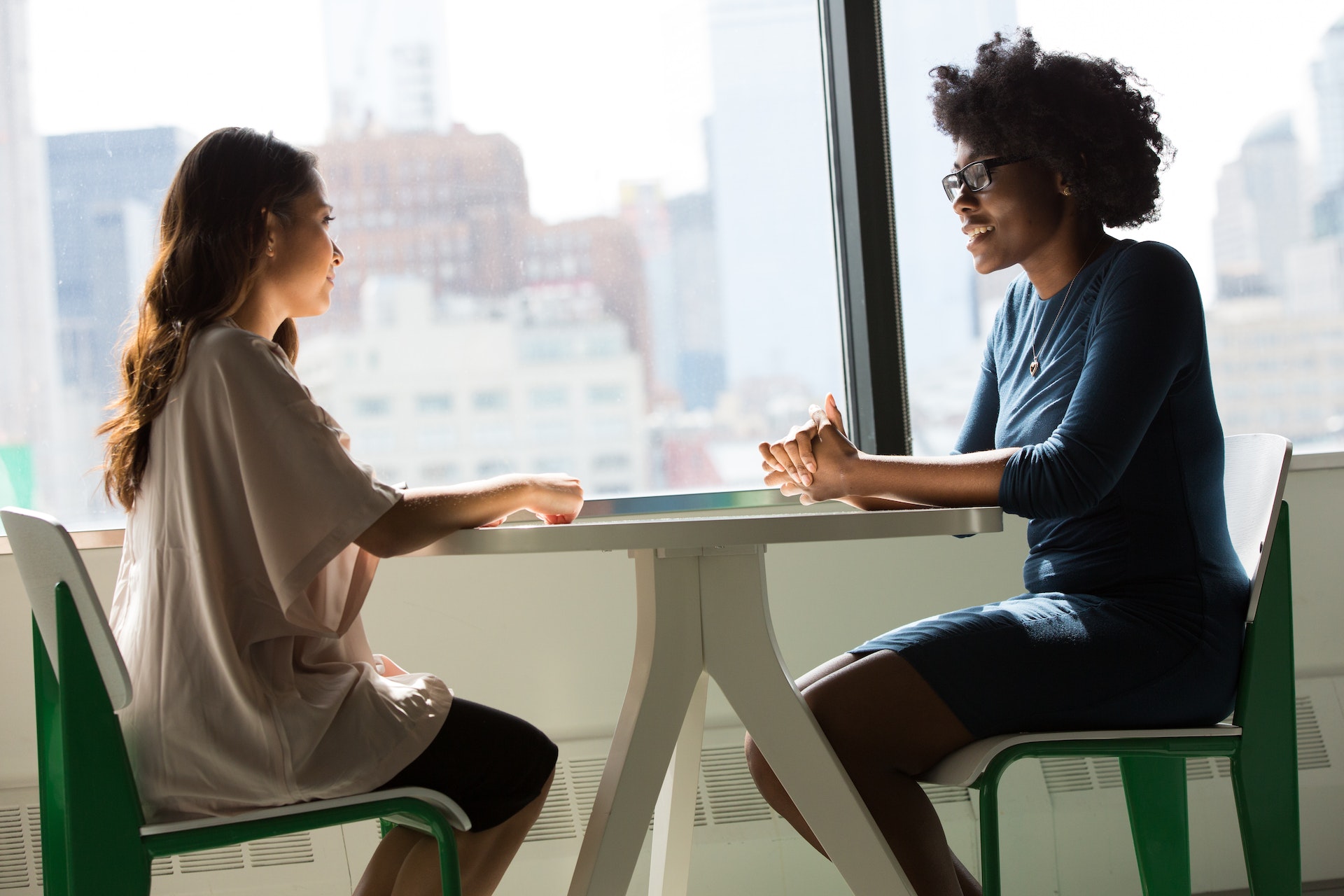 Two women colleagues of different ethnicities discussing workforce diversity