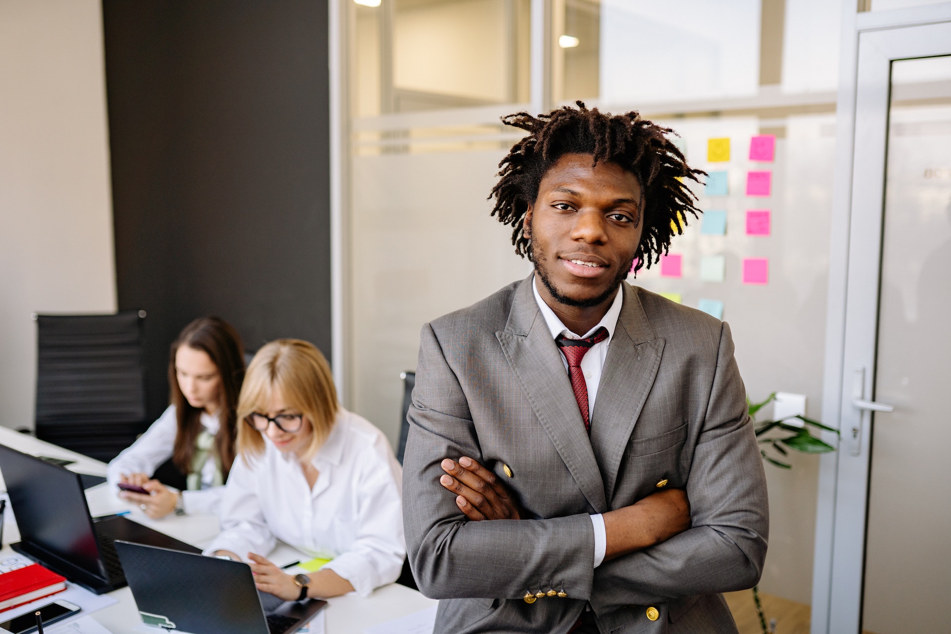 Black professional male people manager, two women employees in background